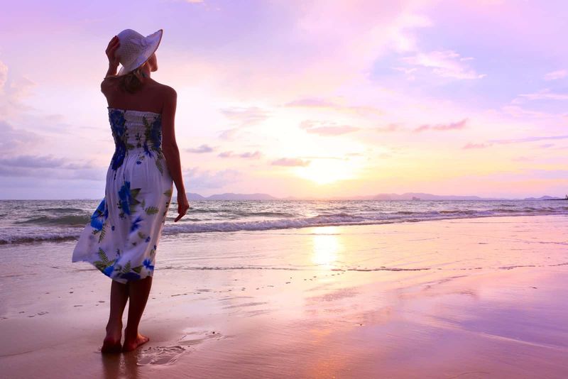 Eine Frau mit Hut auf dem Kopf steht am Strand