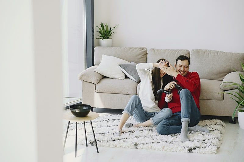Mann und Frau sitzen lachend auf dem Teppich