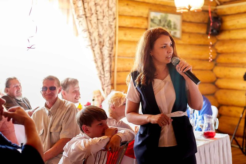 Eine Frau mit langen braunen Haaren hält eine Rede bei einer Hochzeit