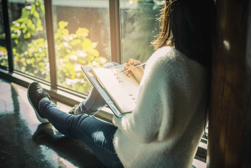Eine imaginäre Frau sitzt am Fenster und schreibt