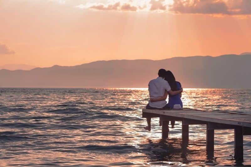 Paar genießt den Sonnenuntergang auf der Holzplattform am Meer