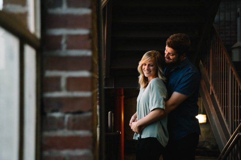 Lächelnder Mann und Frau, die sich in der Nähe der Treppe umarmen