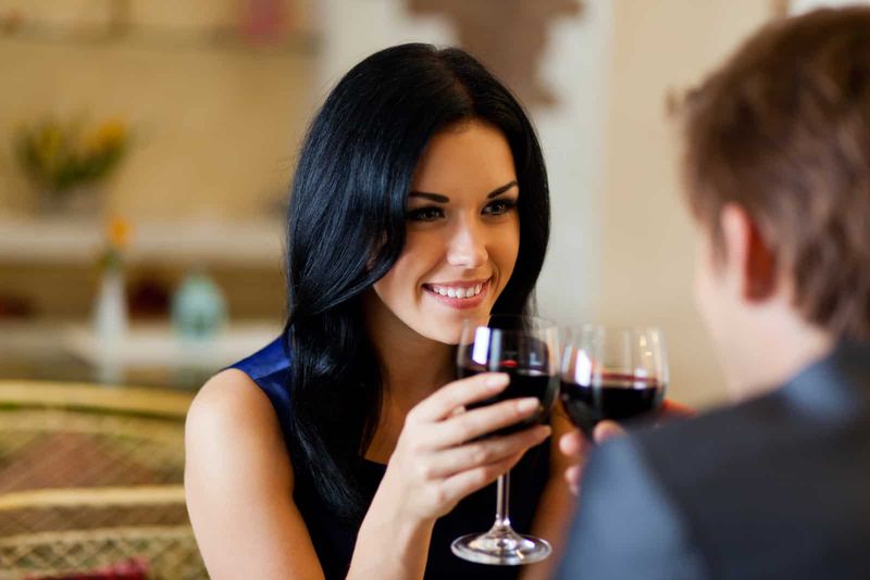attraktive Frau, die Wein trinkt und dem Mann zuhört