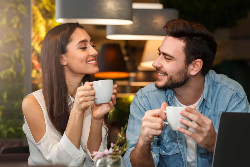 Junge Männer und Frauen trinken Kaffee und flirten
