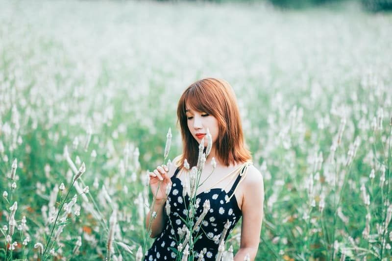 Frau im schwarzen Blumenkleid im grünen Feld