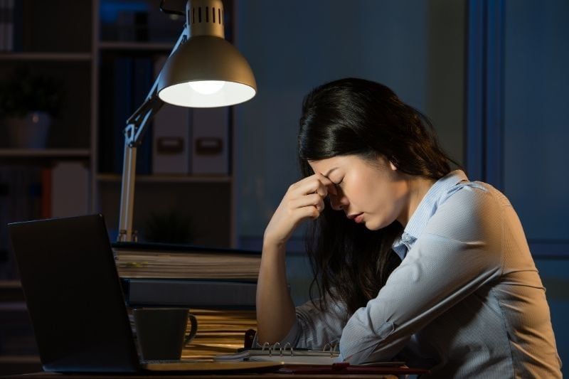 Geschäftsfrau leidet unter Kopfschmerzen und macht Überstunden im Büro