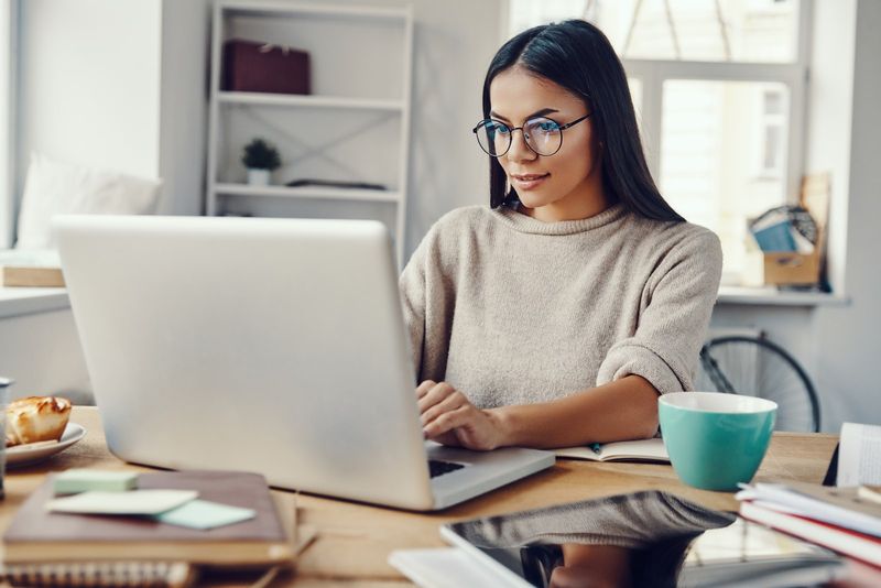 Eine Frau sitzt an einem Laptop und arbeitet