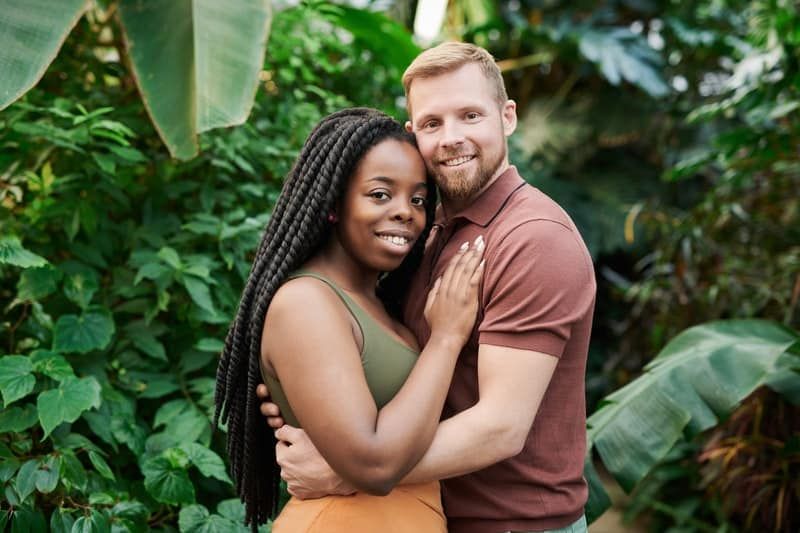 Weißer Mann umarmt schwarze Frau