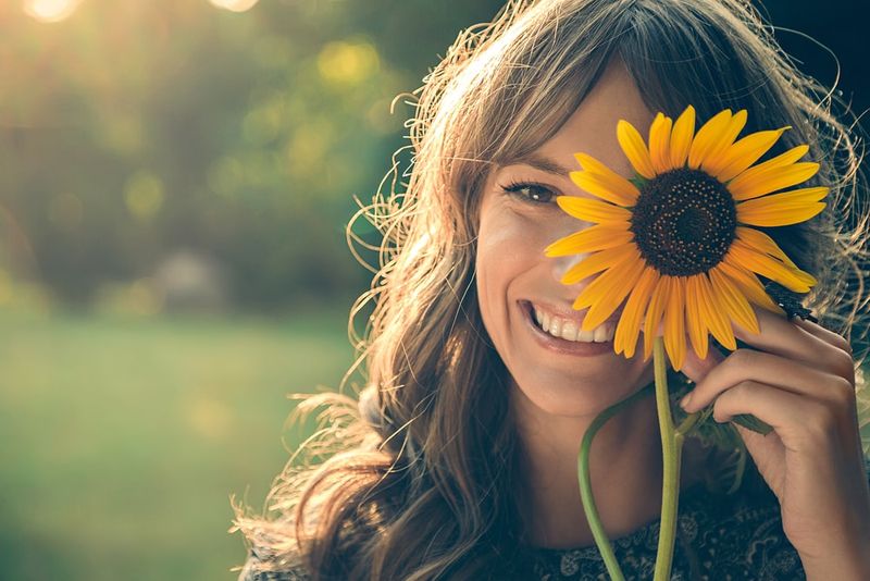 ein Porträt eines lächelnden Mädchens, das eine Sonnenblumenblume hält