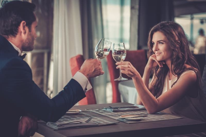 Lächelndes Paar, das einander anschaut, während es im Restaurant ein Glas Wein trinkt