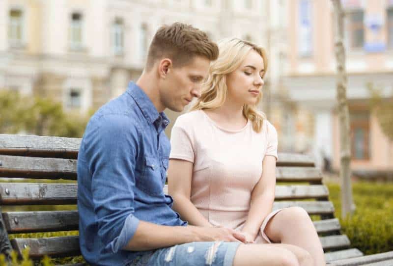 Nachdenkliches Paar sitzt auf einer Parkbank