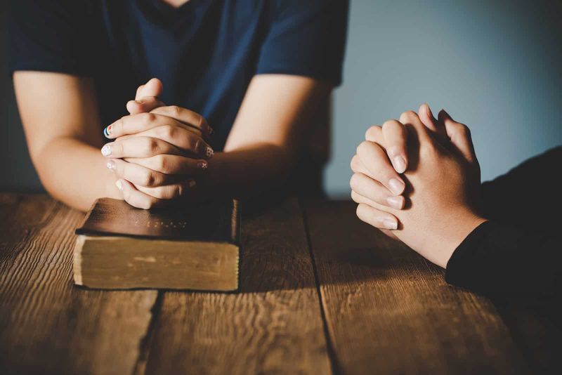 Ehepaar betet zusammen mit der Bibel auf dem Tisch