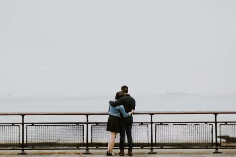 Mann und Frau umarmen sich, während sie in der Nähe des Zauns stehen