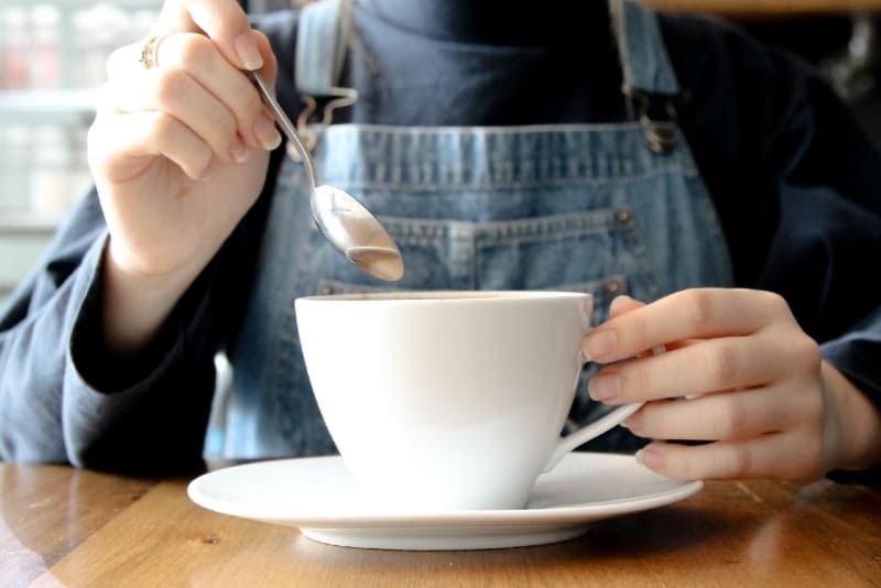 Frau hält weiße Tasse Kaffee im Café