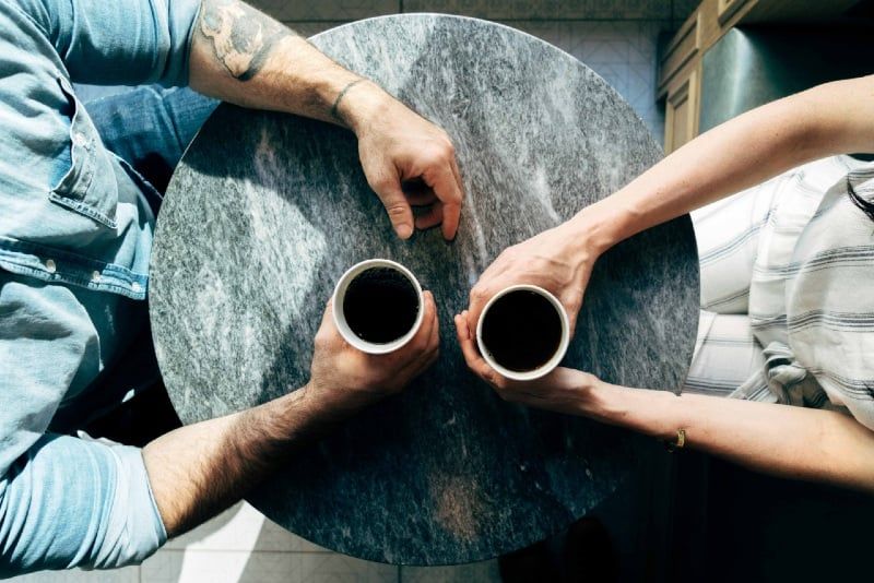 Mann und Frau halten Tassen Kaffee im Café