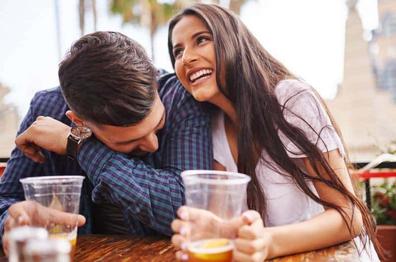 lächelndes Paar, das Bier aus Plastikglas trinkt