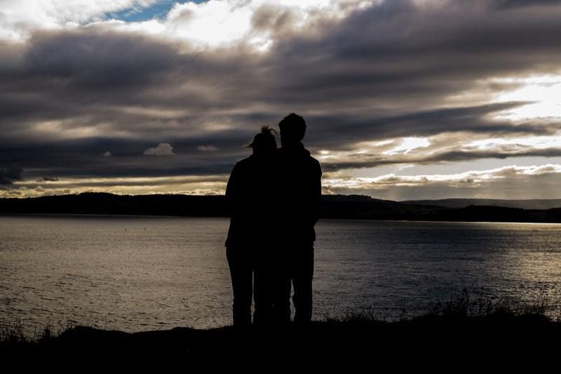Silhouette eines Paares, das sich vor dem See umarmt