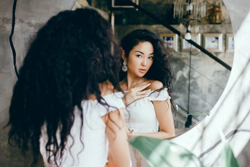 Eine schöne asiatische Frau schaut in den Spiegel