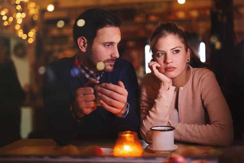 Mann schaut seine nachdenkliche Freundin im Café an