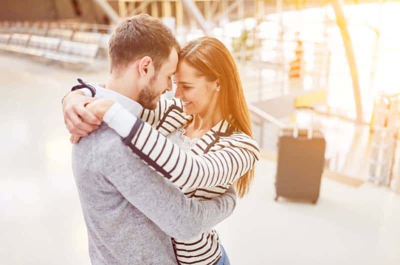 Glückliches Paar umarmt sich am Flughafen