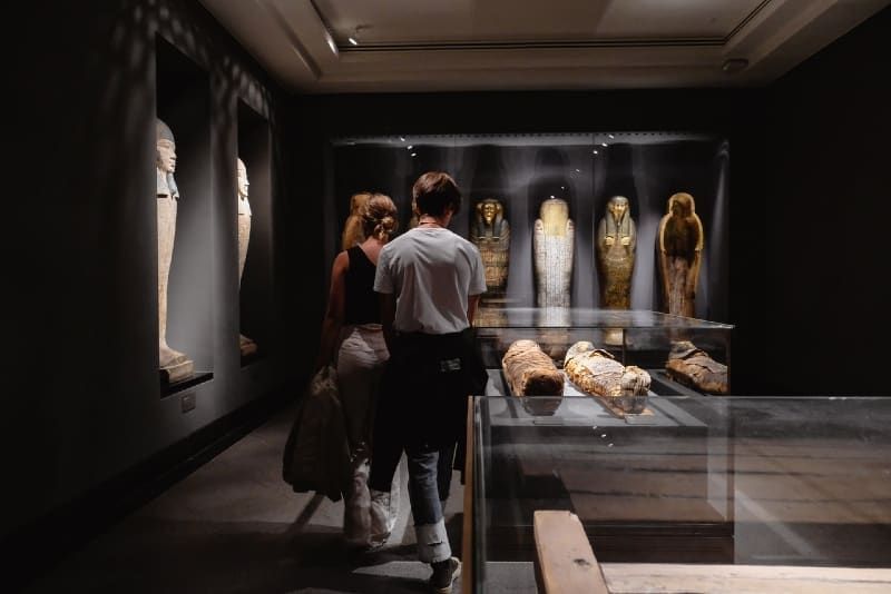 Mann und Frau, die in der Nähe von Mumien im Museum spazieren
