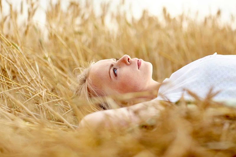 Eine blonde Frau liegt in einem Weizenfeld