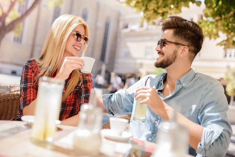 Mann und Frau trinken Kaffee, während sie im Café im Freien sitzen