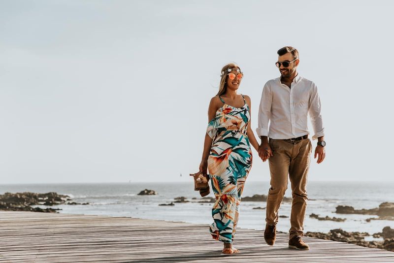 Mann und Frau halten sich an den Händen, während sie am Meer spazieren gehen