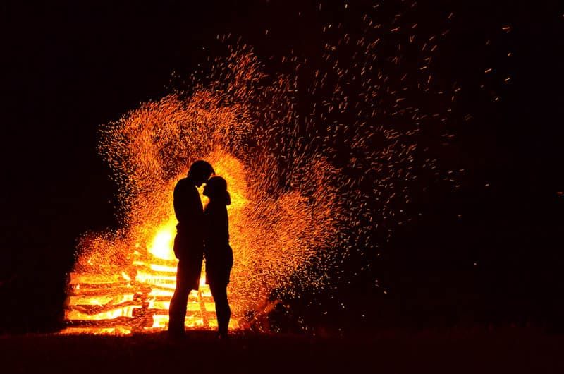 Silhouette von Mann und Frau, die neben Flammen stehen