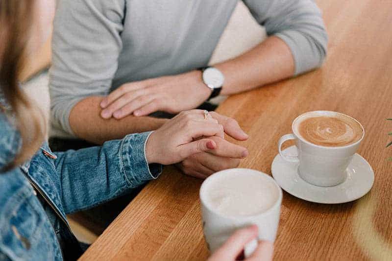 Foto einer Frau, die im Café die Hand eines Mannes hält