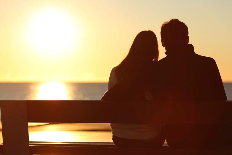 Paar umarmt und beobachtet die Sonne am Strand