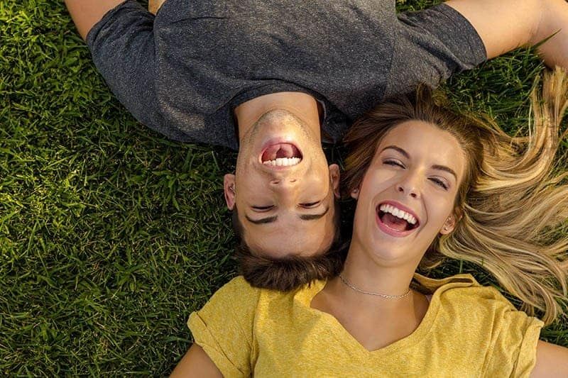 lächelndes Paar, das zusammen auf dem Gras liegt