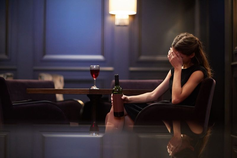 Einsame junge Frau traurig mit einer Flasche Rotwein in einem Luxushotel