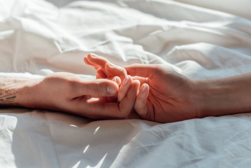 Paar im Bett, Händchen haltend