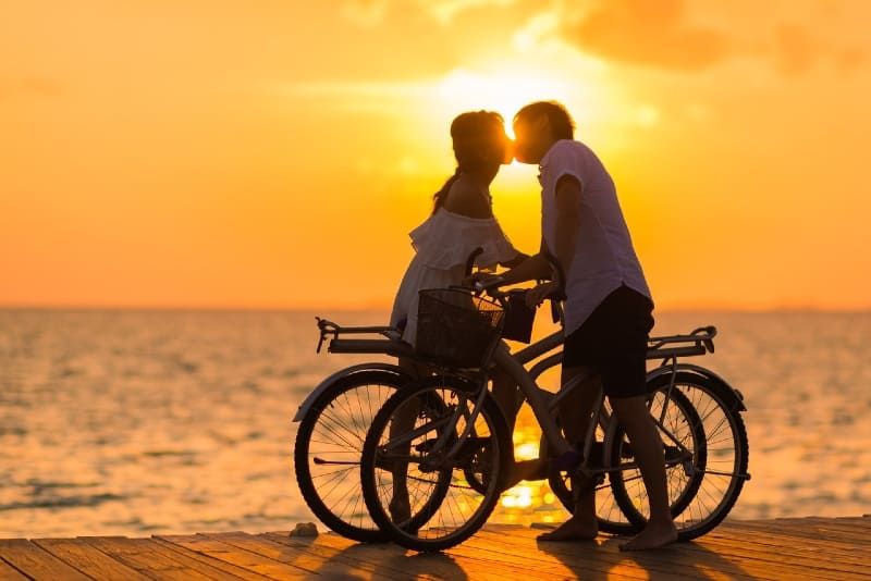 Mann und Frau küssen sich auf dem Dock, während sie Fahrräder halten