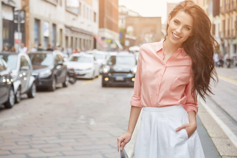 Eine Frau mit langen braunen Haaren steht auf der Straße und lacht