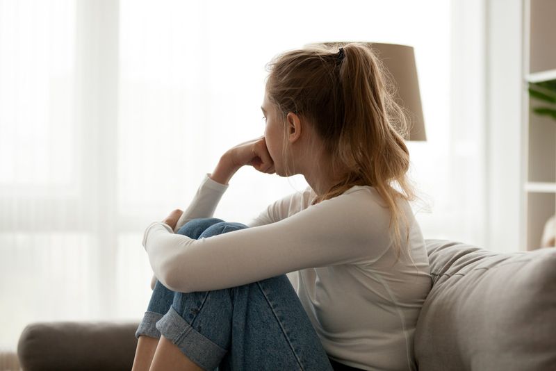 Eine Frau mit langen braunen Haaren sitzt auf der Couch