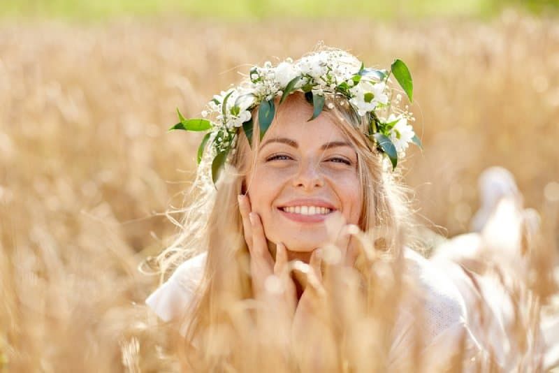 Blonde lächelnde Frau, die auf einem Getreidefeld liegt