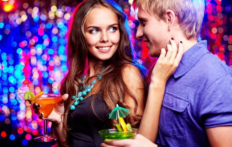 Mädchen mit einem Cocktail flirtet mit ihrem Freund auf einer Party