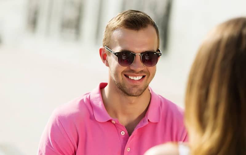 Schöner Mann lächelnd, trägt rosa Hemd, vor einer Frau