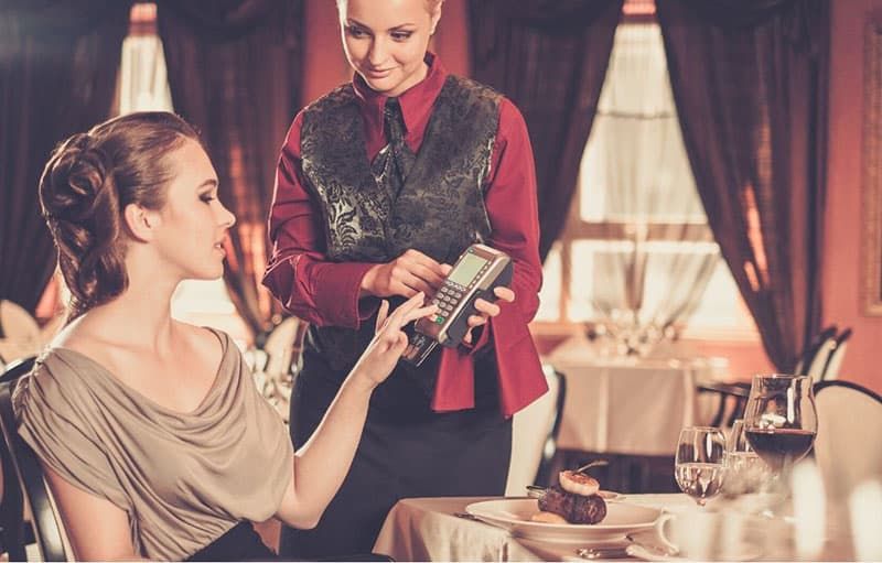 Frau bezahlt Rechnung mit Karte in einem Restaurant