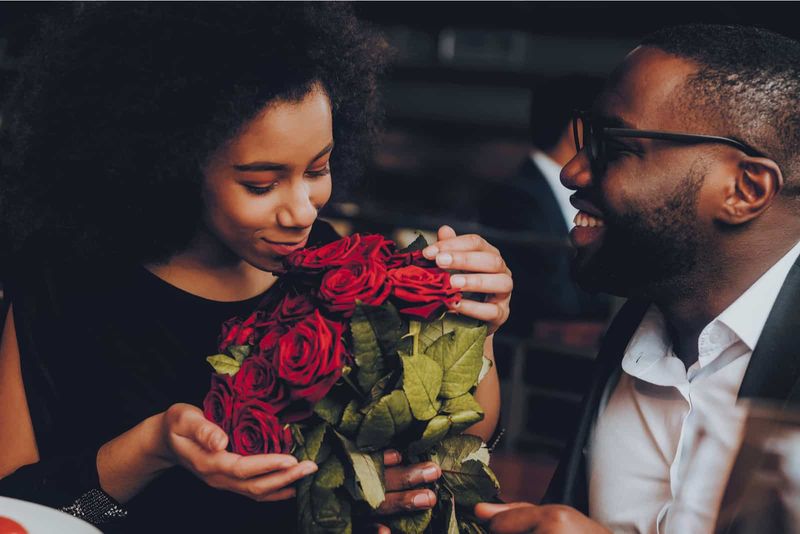 Freund überrascht seine Freundin beim Date mit roten Rosen