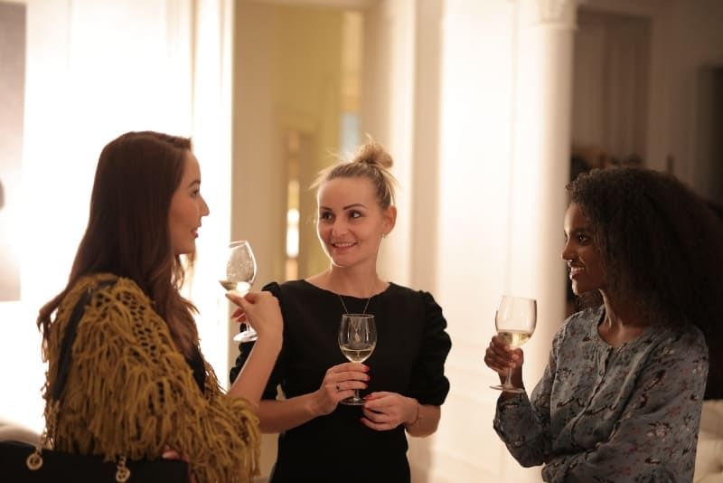 Drei Frauen halten Weingläser in der Hand und reden