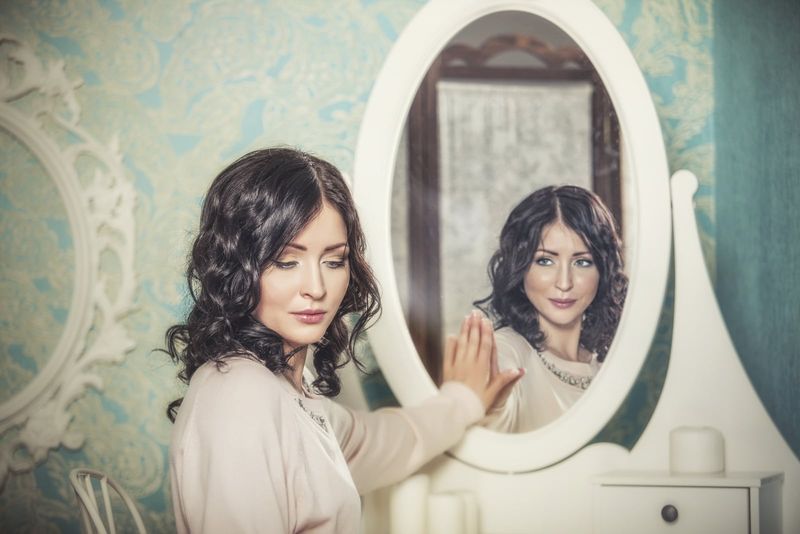 eine Frau, die neben einem Spiegel steht