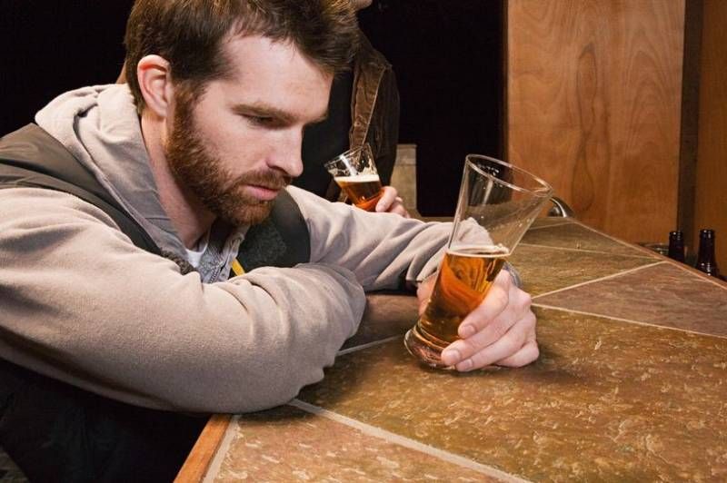 Mann blickt auf ein Glas Bier