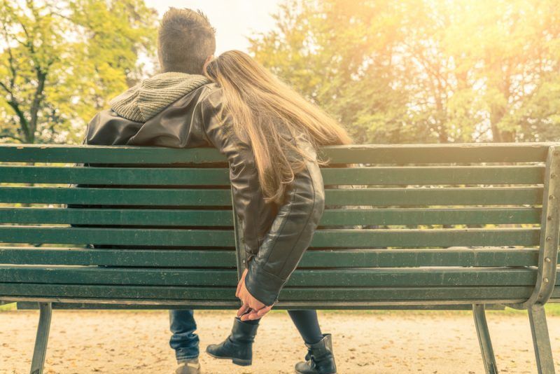 Ein verliebtes Paar sitzt auf einer grünen Bank im Park