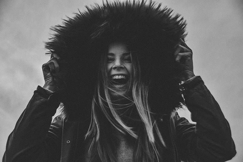Lächelnde Frau zieht sich draußen eine Kapuze über den Kopf