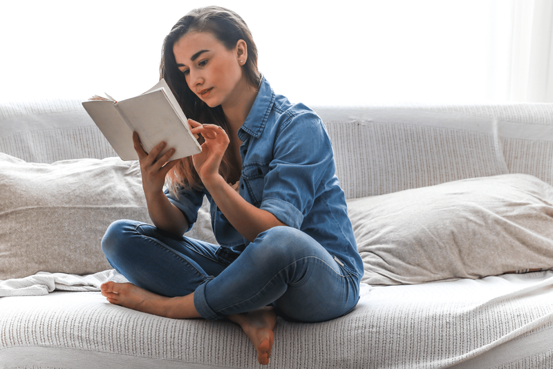 Eine Frau sitzt auf der Couch und liest ein Buch