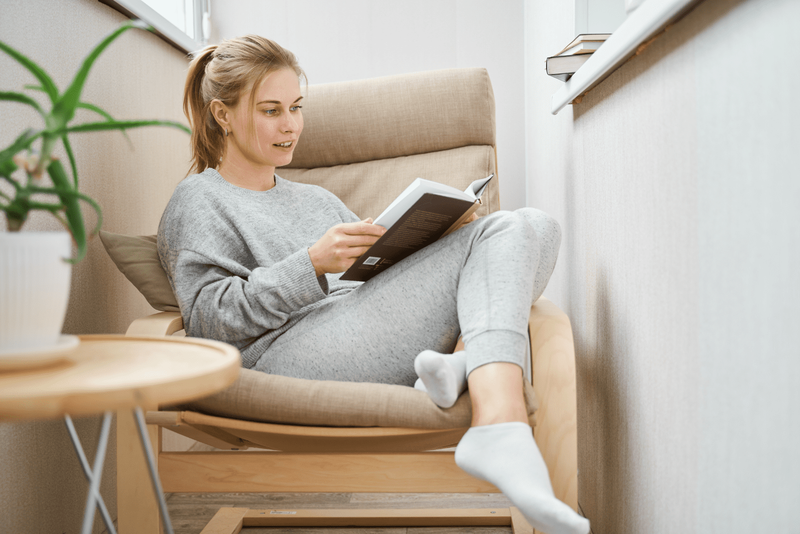 Eine schöne Frau mit gebundenen Haaren sitzt auf einem Sessel und liest ein Buch