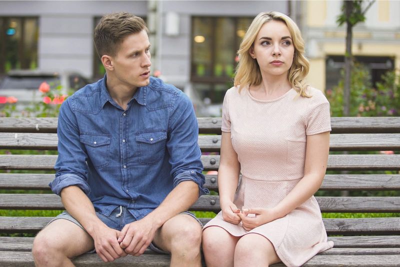 Ein Mann und eine Blondine trennen sich auf einer Parkbank